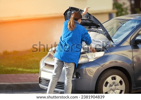 Woman open car hood, steam from the engine compartment. Woman and broken car, smoking engine, coolant leak, engine overheating.

