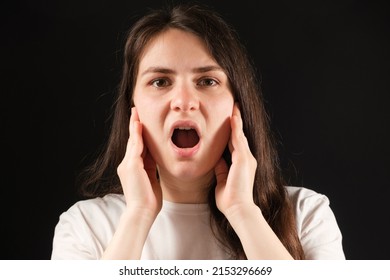 A woman with an open mouth holds her cheeks with her hands, exercises for dysfunction of the temporomandibular joint - Shutterstock ID 2153296669