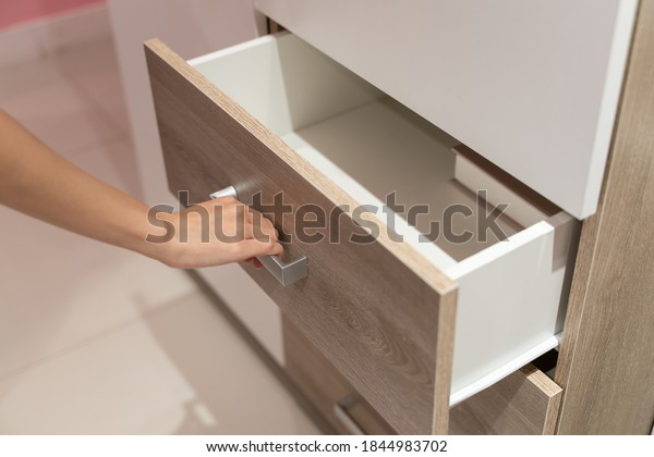 Woman\
open shelf, pull open drawer wooden in\
cabinet.