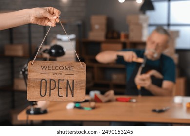 Woman with OPEN sign in shoemaker's workshop, closeup - Powered by Shutterstock