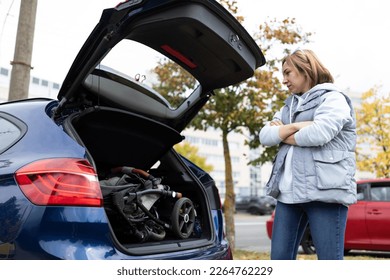 woman at the open trunk of a car with a baby stroller inside