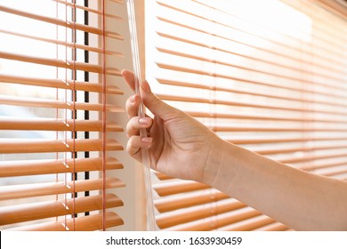 Woman Opening Blinds On Window