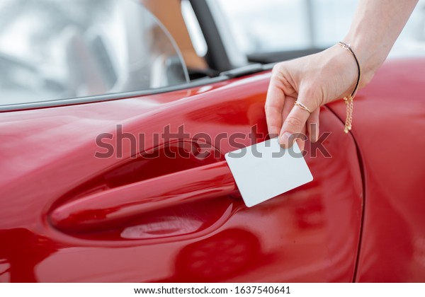 Woman\
opening car door with a plastic card, close-up on hands and door\
handle. Concept of keyless car access with a\
card