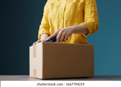 Woman Opening A Delivery Box Using A Cutter