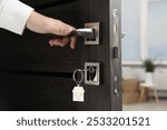 Woman opening door with key and house shaped keychain, closeup