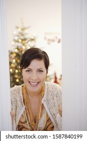 Woman Opening Double Doors With Christmas Tree In Background