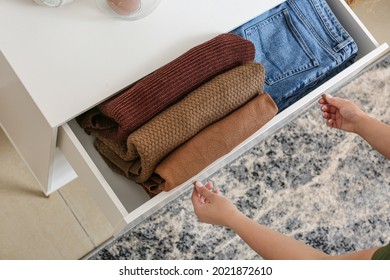 Woman Opening Drawer With Clothes At Home