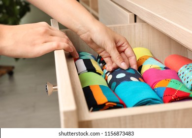 Woman opening drawer with different colorful socks indoors, closeup