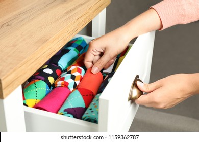 Woman opening drawer with different colorful socks indoors, closeup