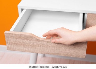 Woman opening empty desk drawer indoors, closeup