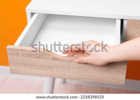 Woman opening empty desk drawer indoors, closeup