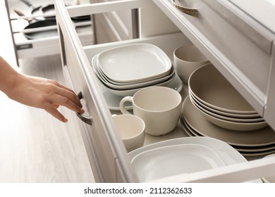 Woman Opening Kitchen Drawer With Clean Dishes, Closeup