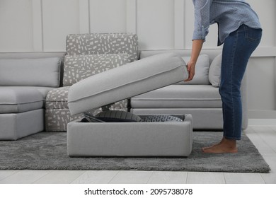 Woman opening modular sofa section with storage in living room, closeup