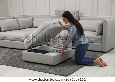 Woman opening modular sofa section with storage in living room