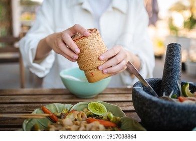 Woman Opening Sticky Rice Bamboo Container While Having A Three Course Meal In A Thai Restaurant Closeup