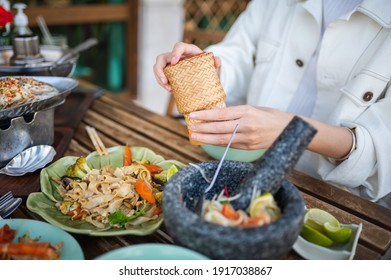 Woman Opening Sticky Rice Bamboo Container While Having A Three Course Meal In A Thai Restaurant Closeup