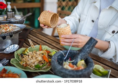 Woman Opening Sticky Rice Bamboo Container While Having A Three Course Meal In A Thai Restaurant Closeup