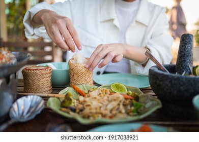 Woman Opening Sticky Rice Bamboo Container While Having A Three Course Meal In A Thai Restaurant Closeup