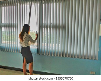 Woman opening the Vertical light curtain or blinds to capture the scenery outside.