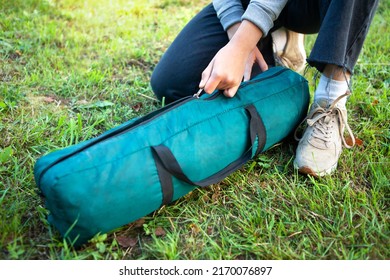 A Woman Opens A Cover With A Tent On The Grass. Close-up Of Her Hands Unzip The Zipper. Tourism Concept. Trekking And Camping.