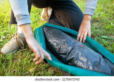 A Woman Opens A Cover With A Tent On The Grass. Close-up Of Her Hands Unzip The Zipper. Tourism Concept. Trekking And Camping.