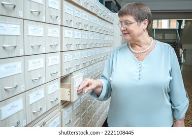 A Woman Opens A Filing Cabinet In Search Of Documents.