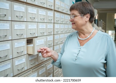 A Woman Opens A Filing Cabinet In Search Of Documents.