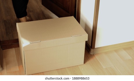 Woman Opens The Front Door And Takes A Large Cardboard Box.