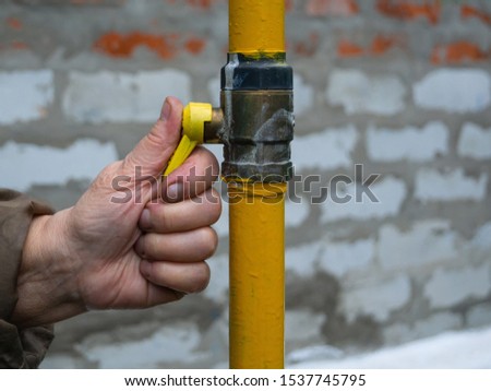 a woman opens a gas tap to supply gas to the house