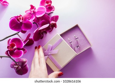 Woman Opens A Gift Box With A Set Of Amethyst Jewellery Surrounded With Orchid