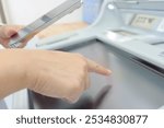 A woman operating an ATM while looking at her smartphone

"Banknotes" are written in Japanese on the ATM panel.