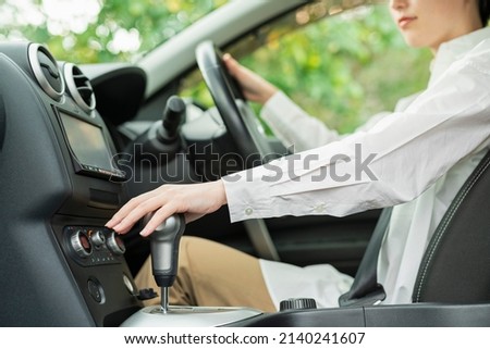 Woman operating the shift lever of a car