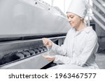 Woman operator checks quality of finished food products. Modern electrical mill machinery for production of wheat flour.