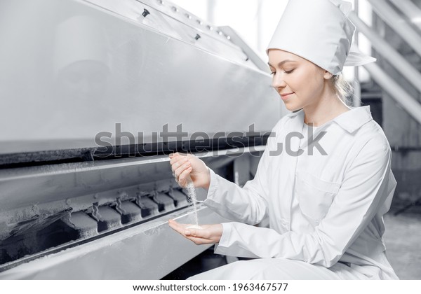 Woman operator checks quality of finished food\
products. Modern electrical mill machinery for production of wheat\
flour.