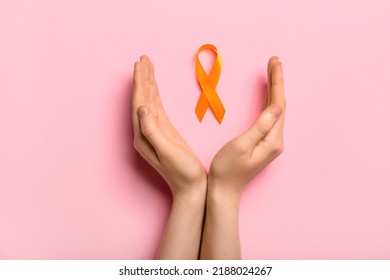 Woman with orange awareness ribbon on pink background. Kidney cancer concept - Shutterstock ID 2188024267