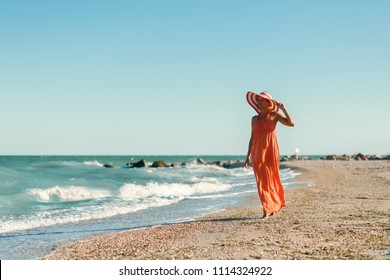 Woman In Orange Dress On Sea Beach