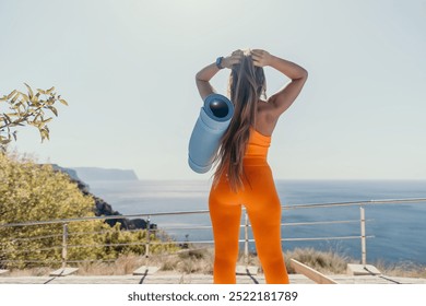 Woman in Orange Outfit Standing on Cliffside Overlooking the Sea - Powered by Shutterstock