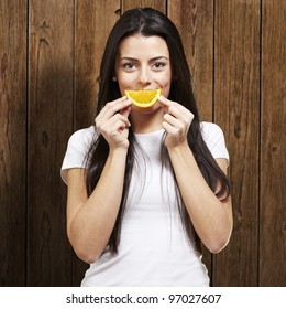 Woman With An Orange Slice As A Smile Against A Wooden Background