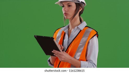 Woman in orange vest with tablet device and hardhat working on green screen - Powered by Shutterstock