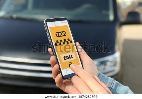 Woman ordering taxi with smartphone on city\
street, closeup