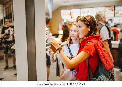 A woman orders food in the touch screen terminal with electronic menu in fast food restaurant - Shutterstock ID 1187772493