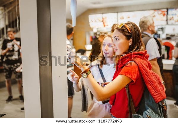 A woman orders food in the touch\
screen terminal with electronic menu in fast food\
restaurant