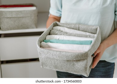 Woman Organizing Clothes In Wardrobe, Putting Shirts In Boxes, Baskets Into Shelves And Drawer. Concept Of Minimalist Lifestyle And Japanese T-shirt Folding System. Tidy Up Capsule Closet