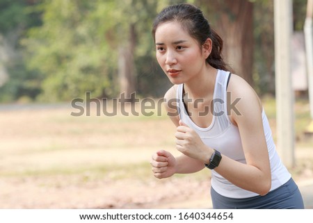 Woman outdoor exercise concept The beautiful Asian woman aged 20 to 25 is an athlete and a runner. Running at a refreshing and relaxing outdoor public park Running sports make the body strong.