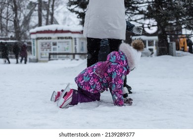 A woman at an outdoor skating rink teaches her child to skate. A woman at an outdoor skating rink teaches her child to skate. and daughter at the ice rink. A child falls on skates. Rear view, no face.