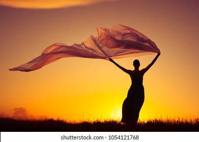 Woman Outdoors In Dress Holding A Long Fabric Blowing In The Wind. Freedom And Serenity Concept. 