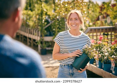 Woman Outdoors In Garden Centre Asking Advice From Sales Assistant Choosing And Buying Rose - Powered by Shutterstock