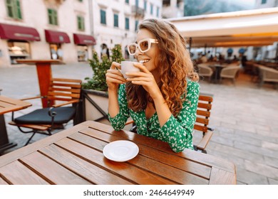 Woman in outdoors street coffee shop cafe sitting at table with cup of coffee, relaxing in restaurant on free time. People, fashion, lifestyle, travel and vacations concept - Powered by Shutterstock