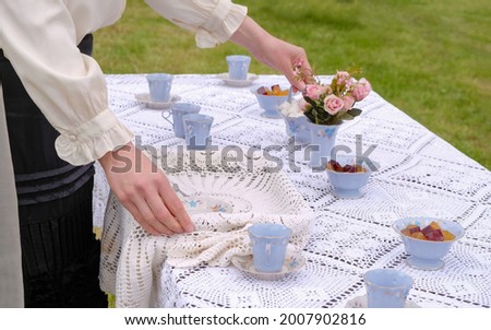 A woman in outmoded clothes serves a tea table. Fragment of hands. Vintage tea party scene. 