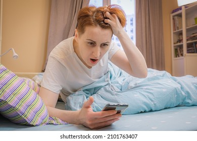 Woman overslept and looks at the time on her smartphone in shock. Middle-aged woman is late due to late awakening. The alarm did not go off on the smartphone.